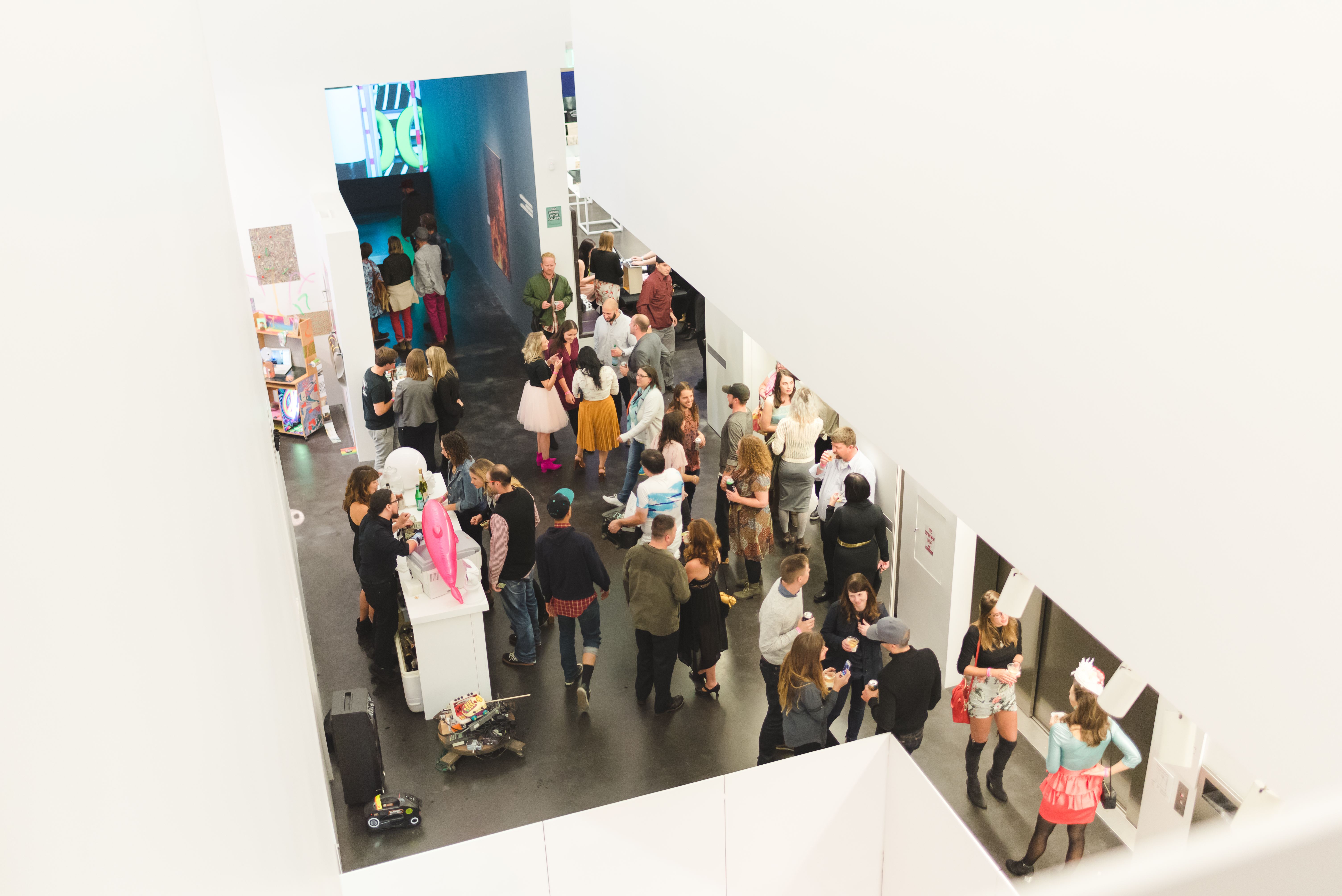 Shot of MCA Denver’s atrium during a busy event taken from high up. Visitors gather in groups talking. 