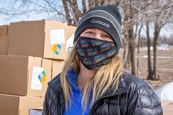 Image of a volunteer standing in front of boxes filled with food donations