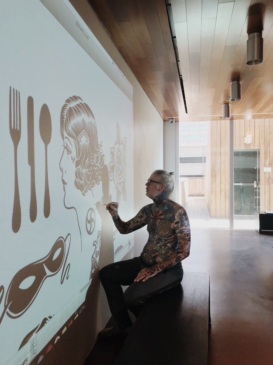 Mike giant traces tattoo like patterns onto a white wall