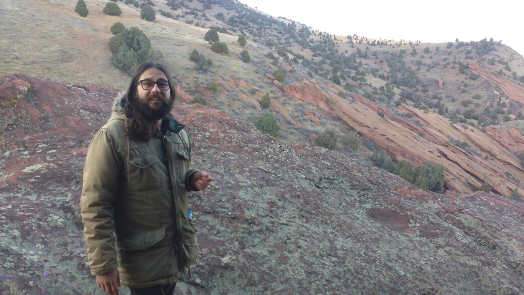 A man is outdoors wearing a green jacket. 