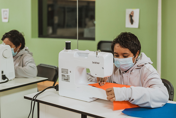 two students in front of sewing machines 