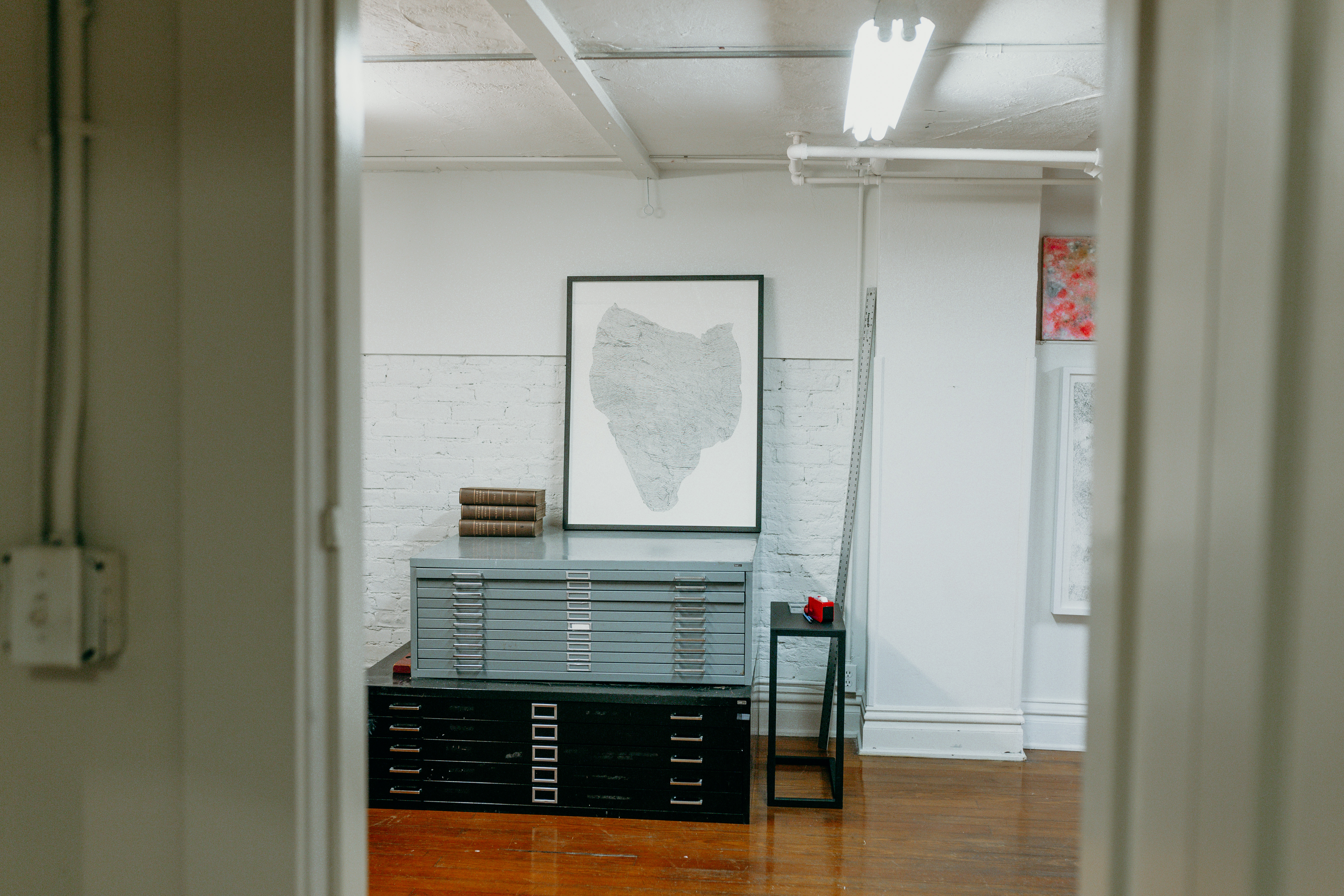 ﻿Black and grey filing cabinets in a room with white painted brick walls. The flooring is wooden and shiny. 