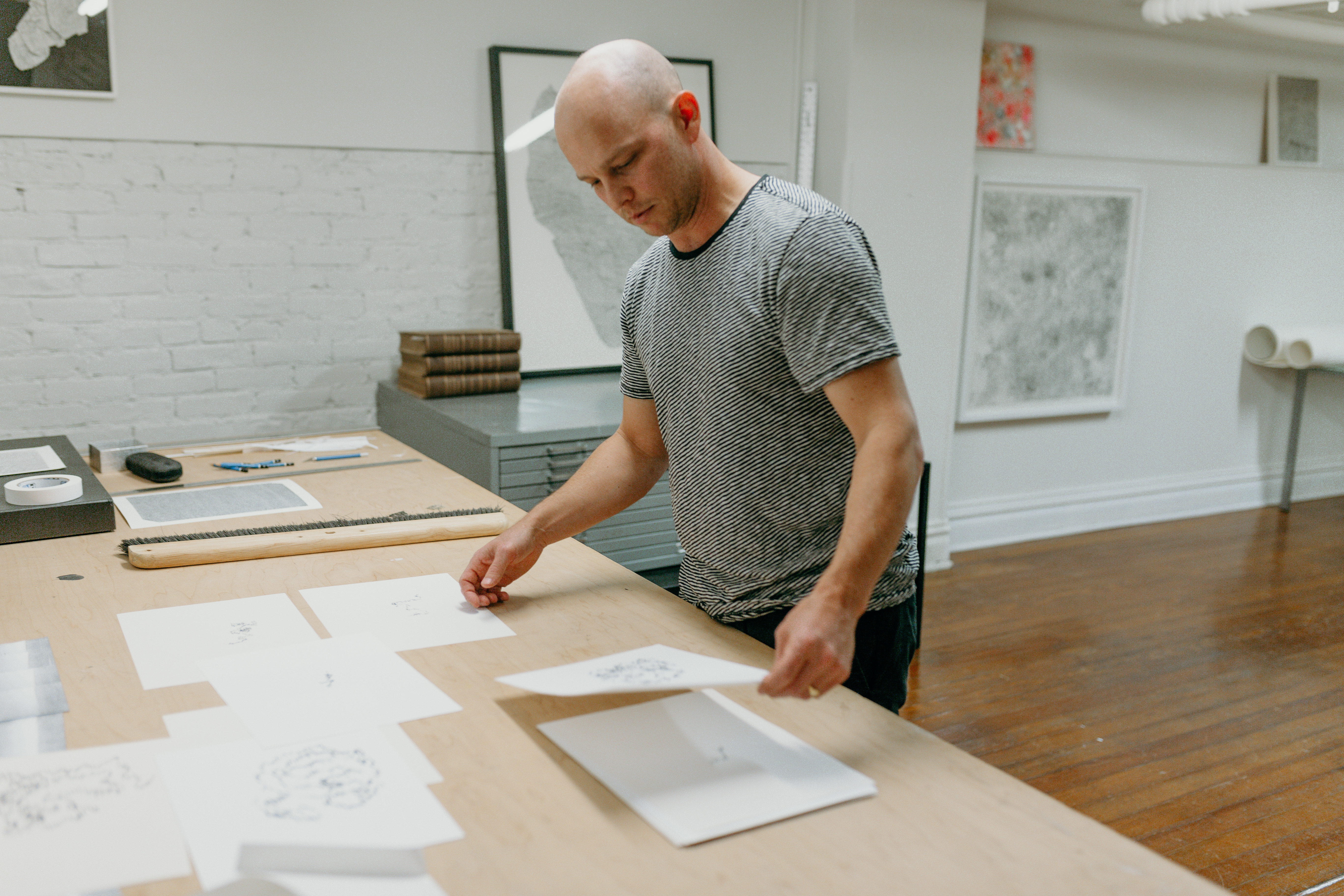 Candid shot of Chris Oatey looking at a piece of paper in an indoor space. In front of him is a desk with several papers strewn about. ﻿