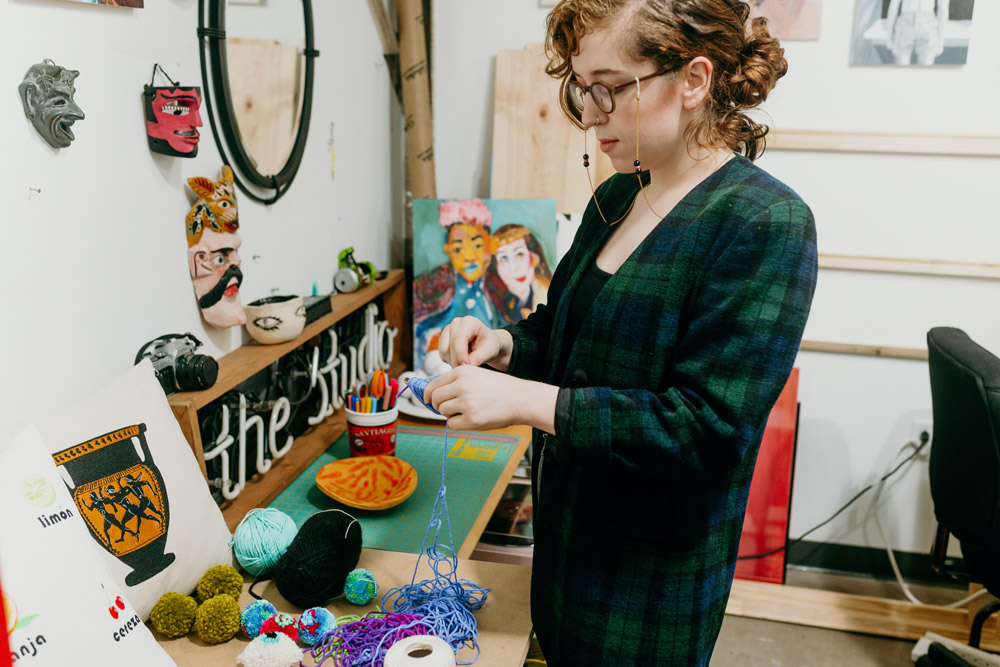 Sierra is holding a spool of blue and purple yarn. 