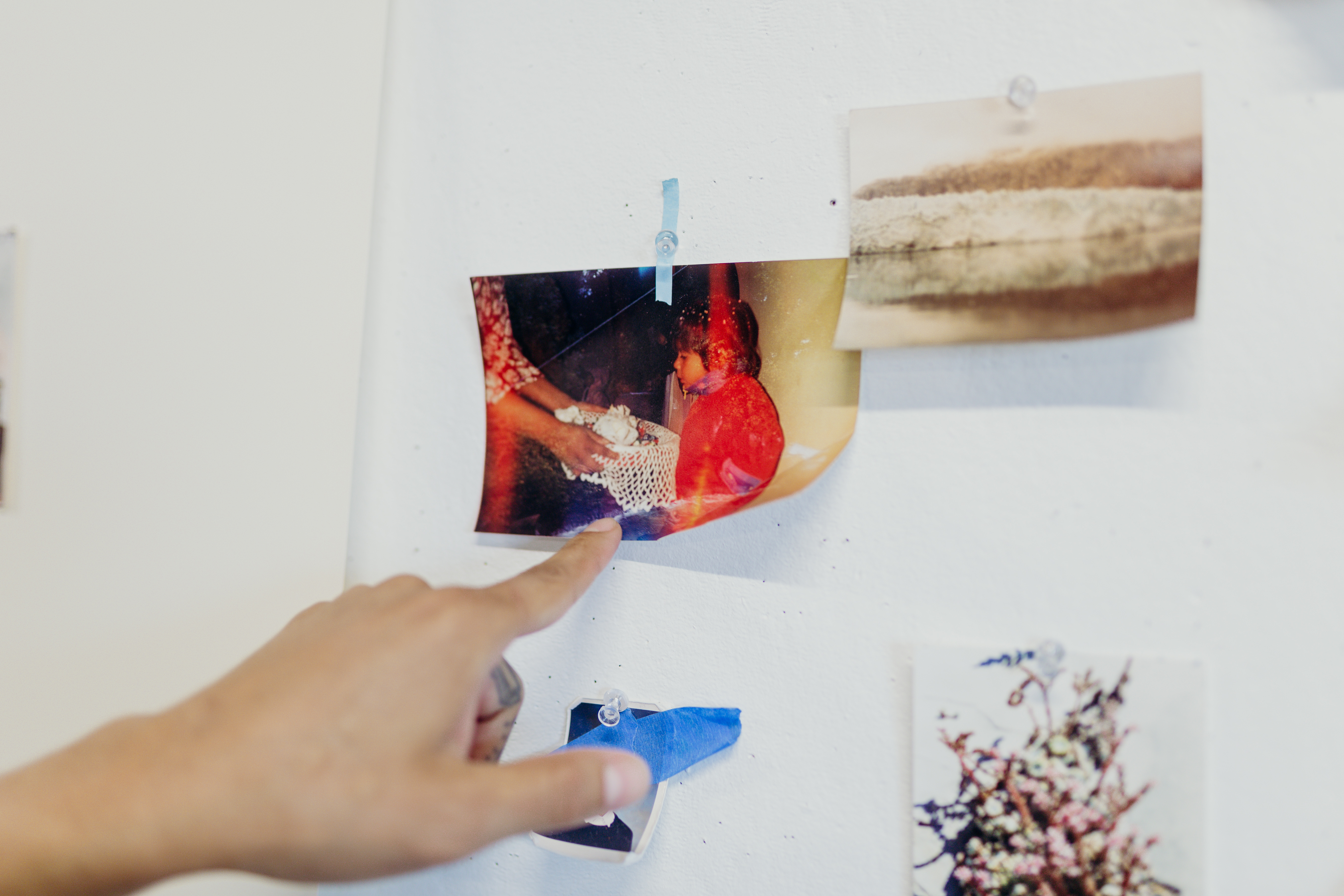 Image of George P. Perez pointing to a photograph on the wall in his studio