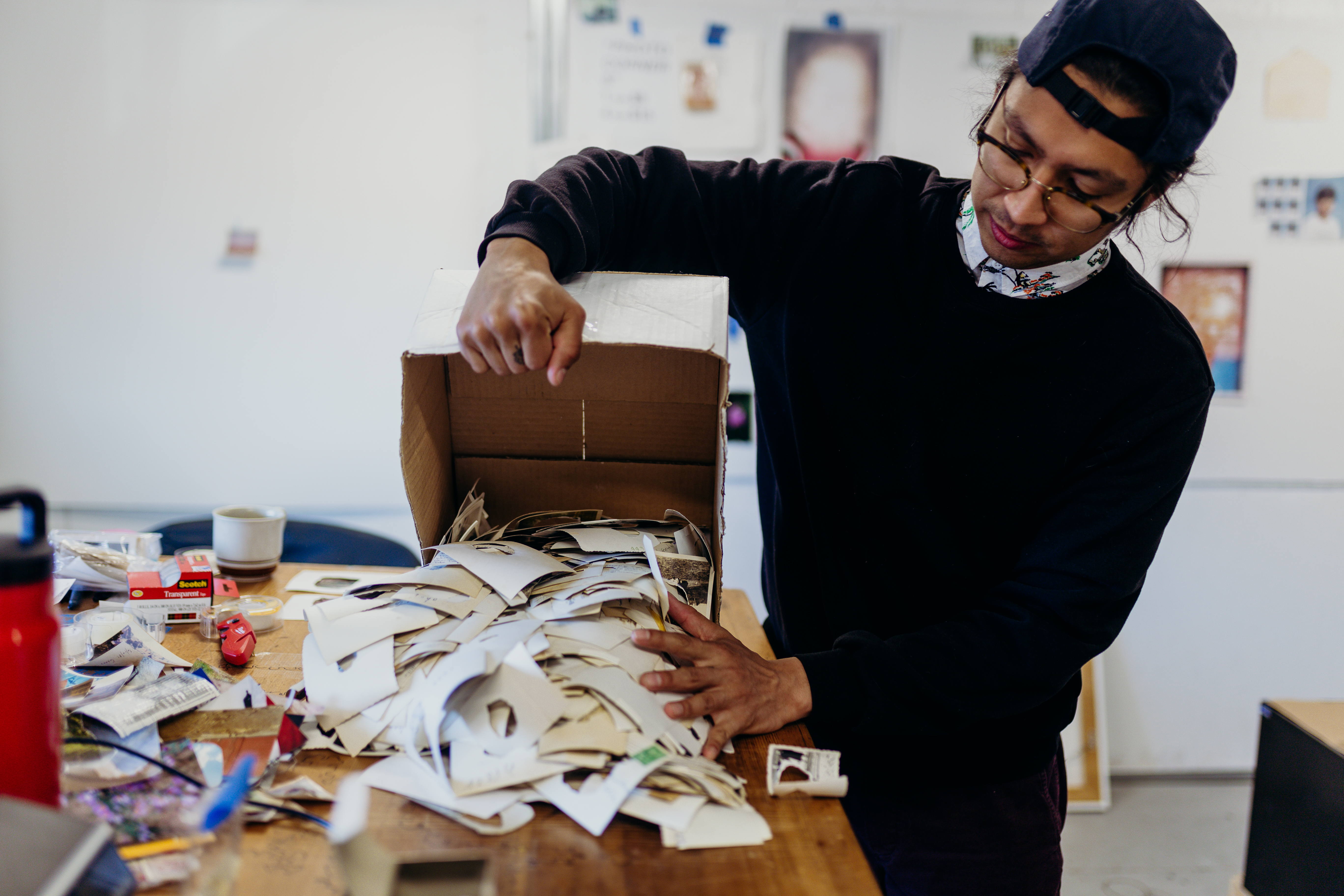 George P. Perez dumping a box of photographs out onto a table