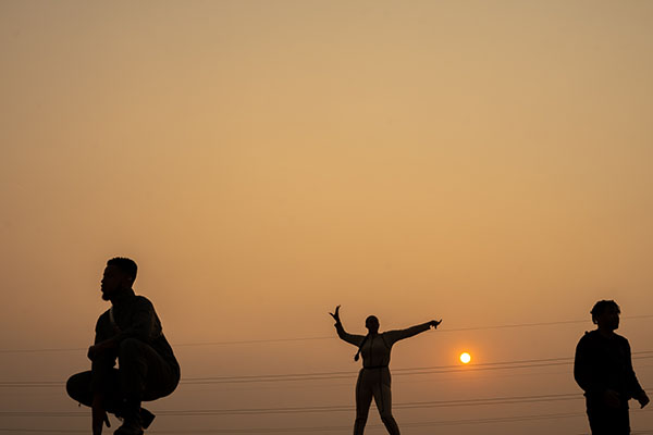 silhouette photo of the band with the orange cast of the sunset behind them