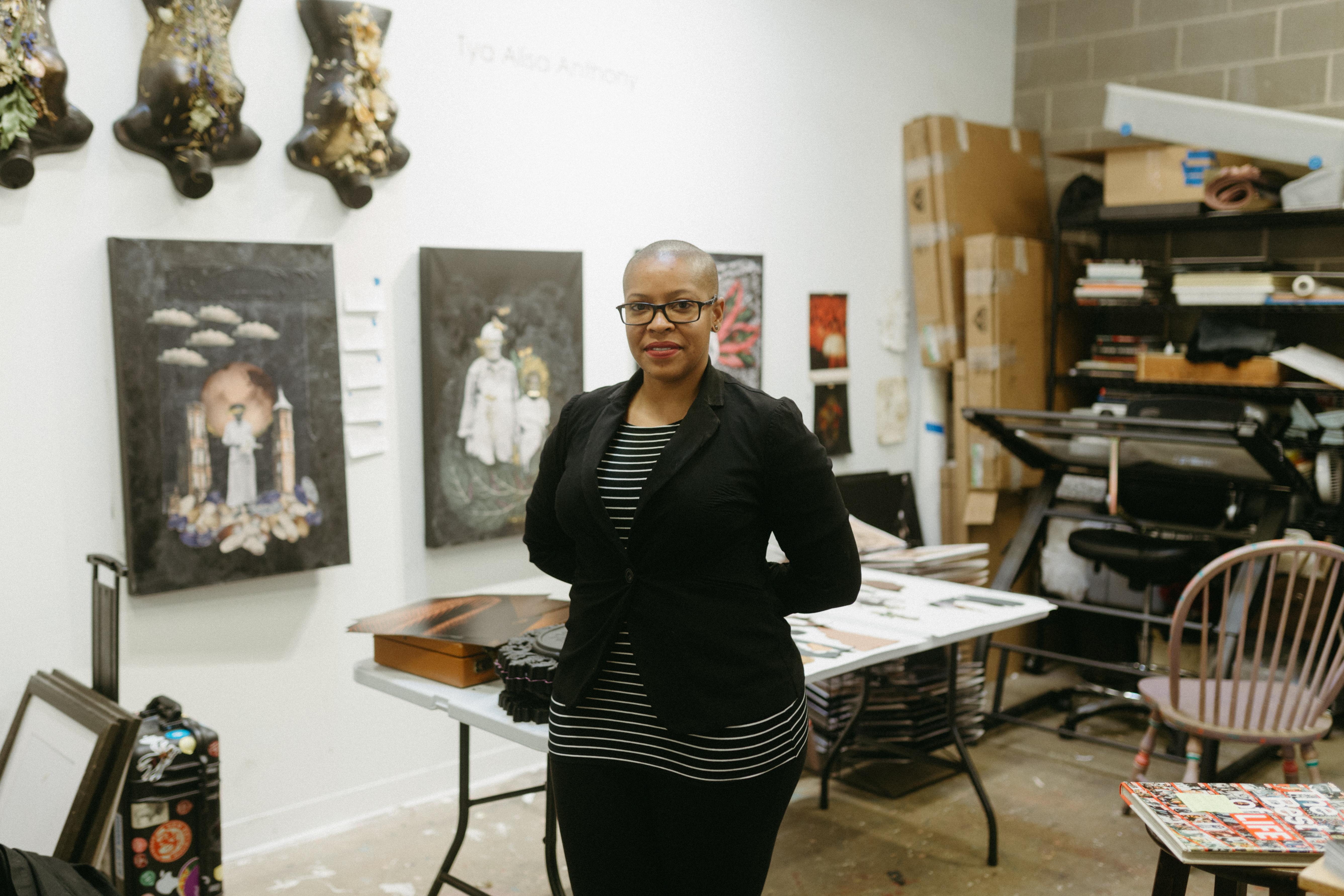 Anthony softly smiling with her studio in the background