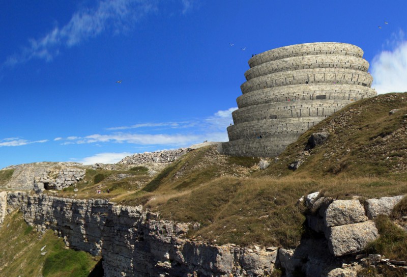 Mass Extinction Memorial Observatory. It is a large round structure situated on a cliffside with many levels. 