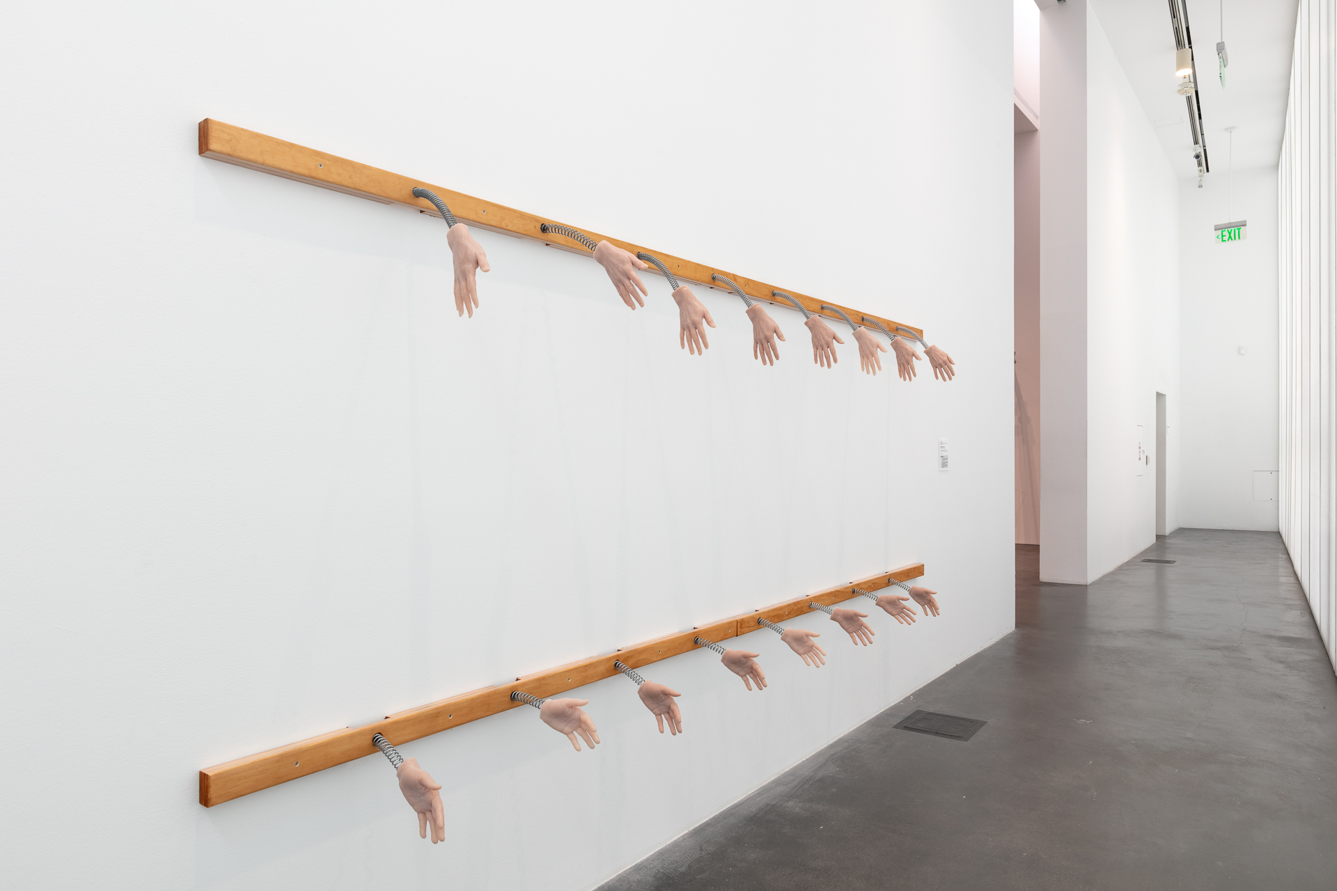 Cast silicone hands affixed to a gallery wall.