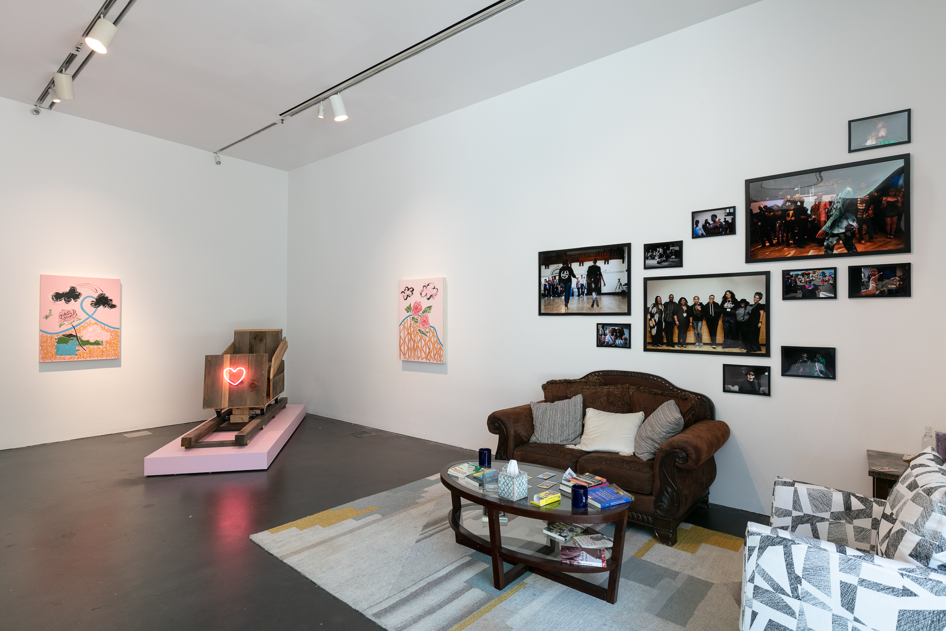 Gallery featuring a wooden roller coaster seat and what looks like a living room setup with a couch, chair, coffee table, and photographs on the wall.