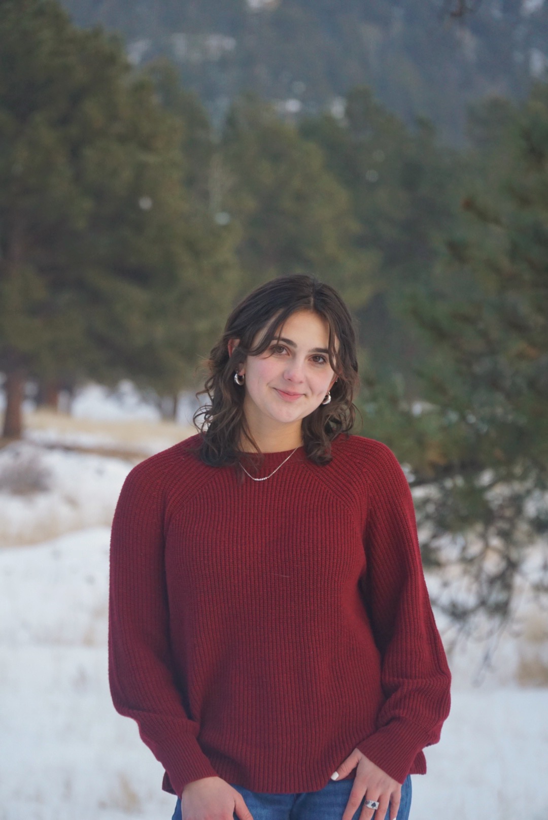 Teen Josie Abramson smiling softly in the woods.