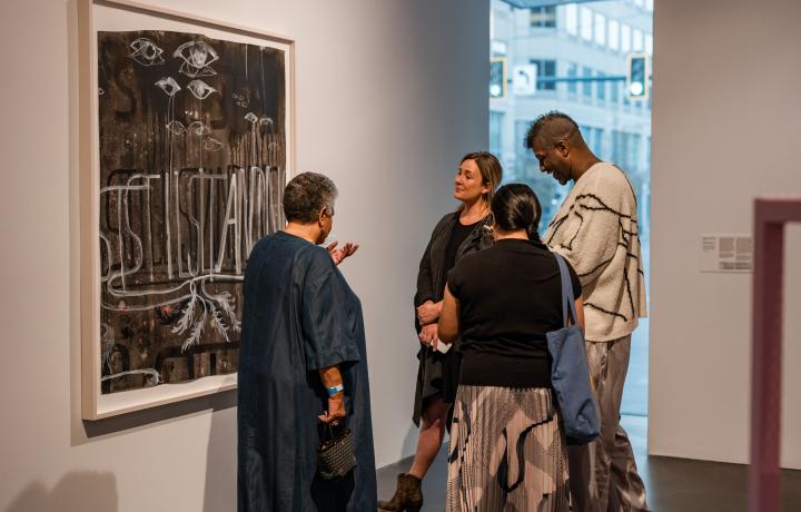 Four people standing and mingling in a gallery.