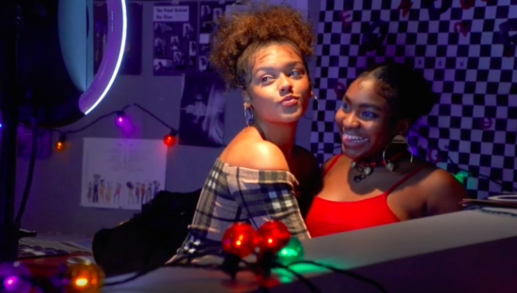 Two young ladies pose in front of a ringlight smiling. 